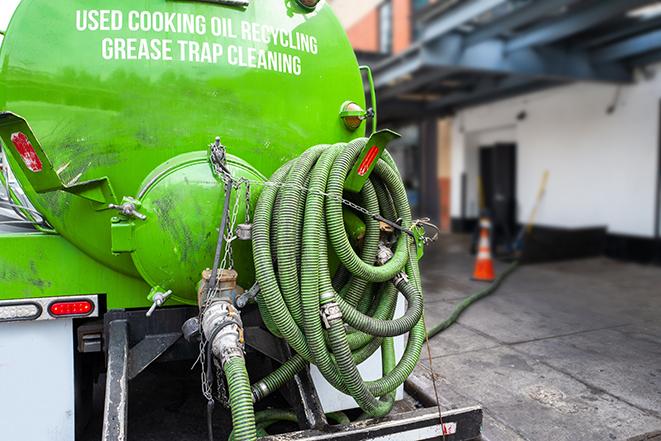 a professional plumber using a pump to empty a grease trap in Deshler